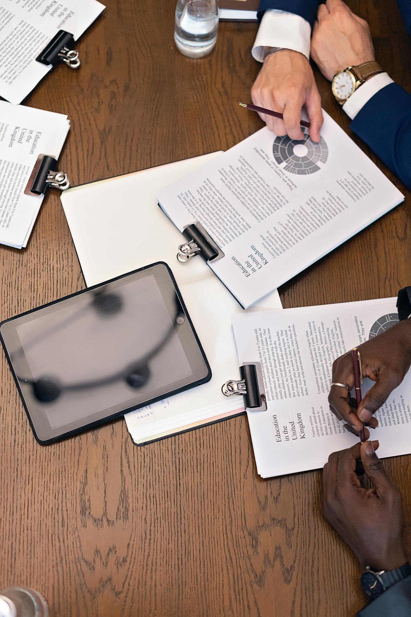 About Top View Of A Business Meeting With Hands Tablets And Documents On A Table. 8730988 1367x2048